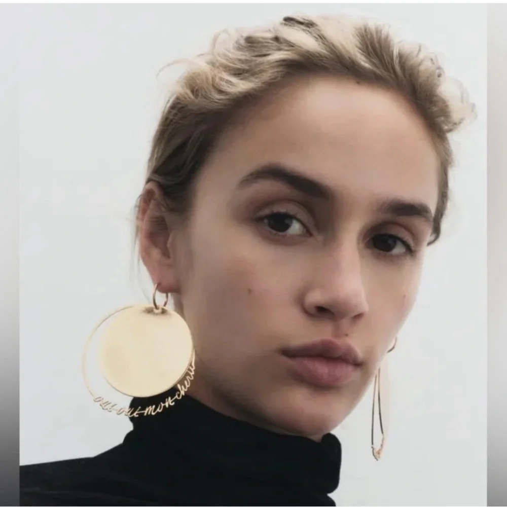 - NWT. Zara Golden Round Flat Metal Earrings with Text Detail.